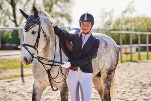 Smiling rider standing close to her calm equitation horse, reflecting trust and harmony