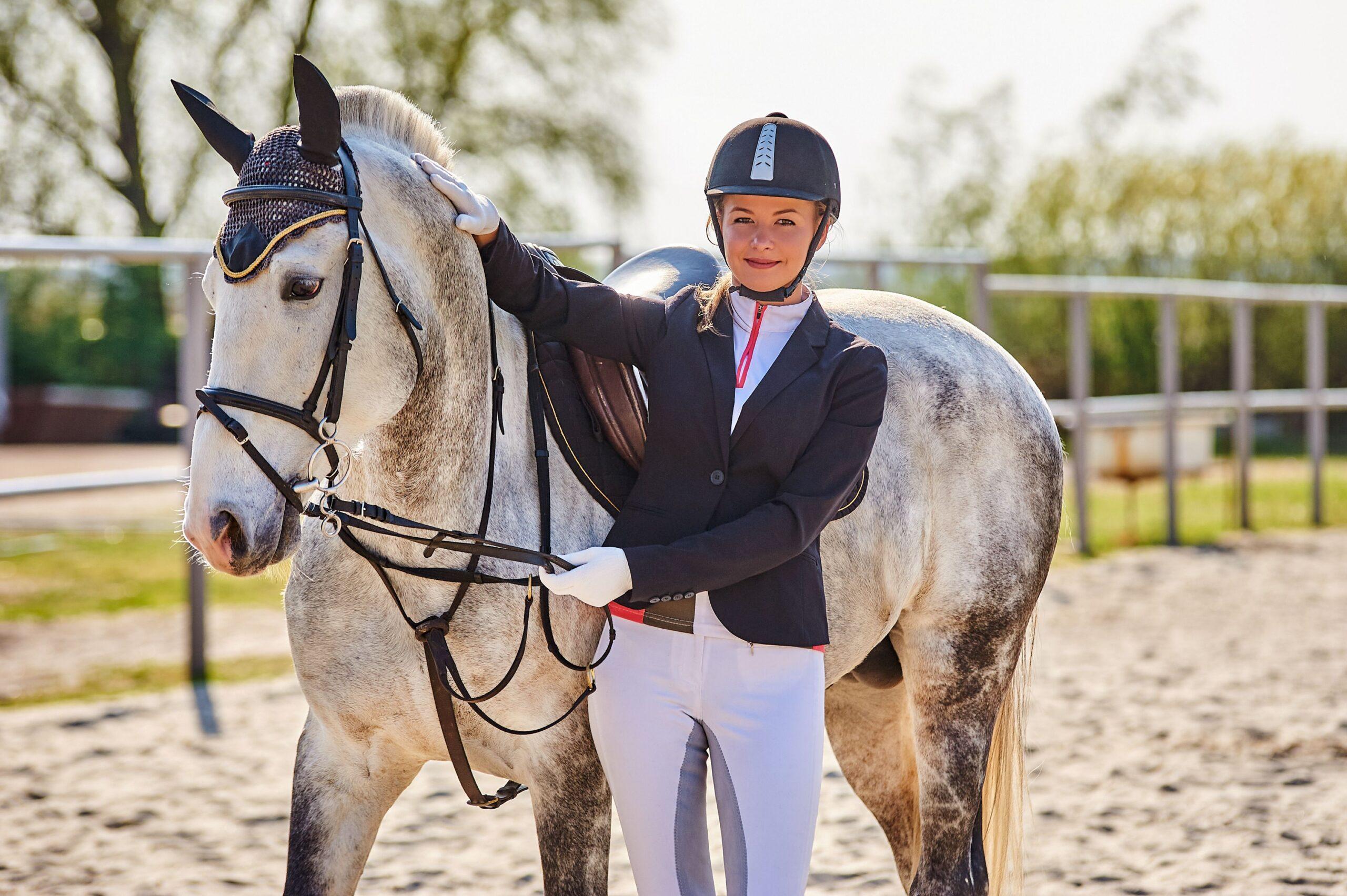 Smiling rider standing close to her calm equitation horse, reflecting trust and harmony