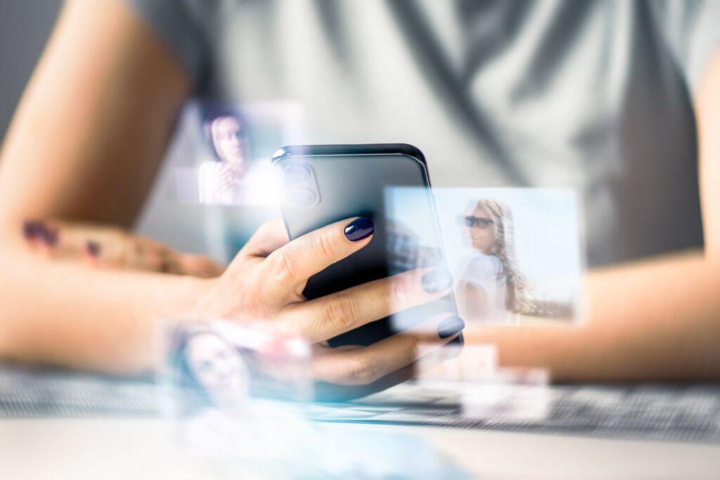 Hand holding a smartphone with projected social profiles, representing digital identity development guided by only fans managers.